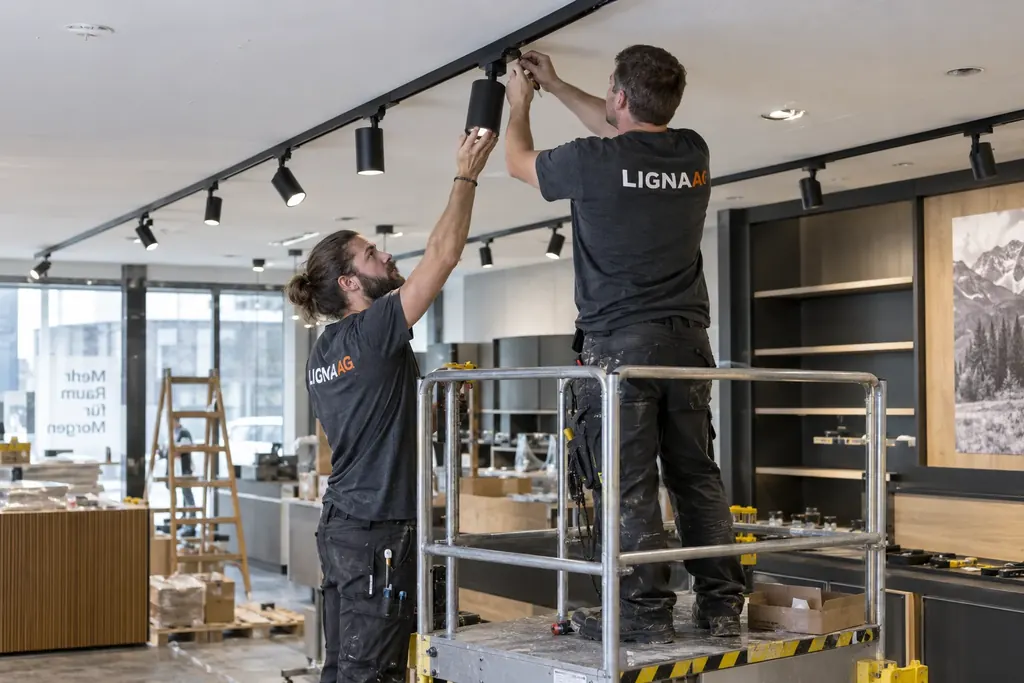 Fachmonteur bei der Montage einer Schienenleuchte an einer Ladendecke